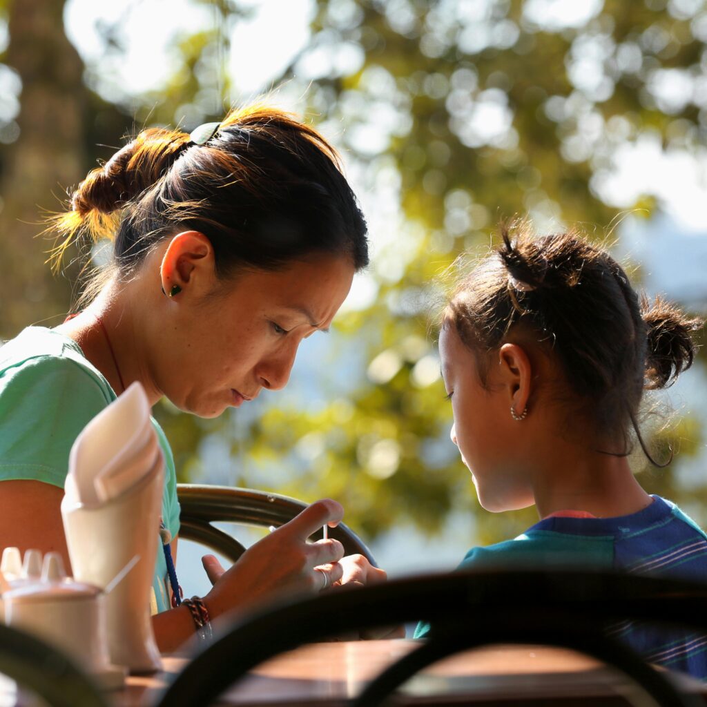 Mother and daughter enjoying quality time outdoors at a cafe.